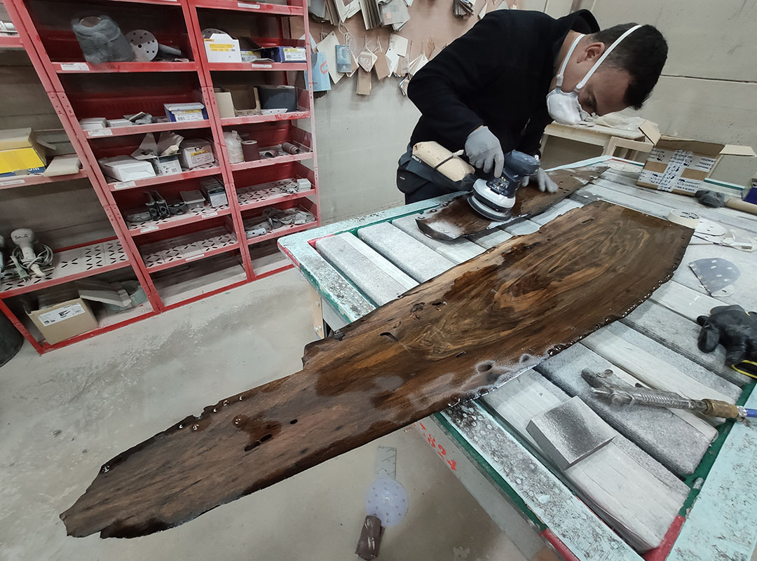 Artesano lijando mesa de nogal y resina azul