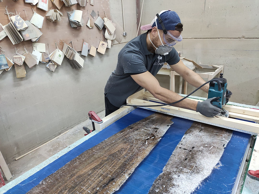 Artesano lijando tabla de nogal y resina azul